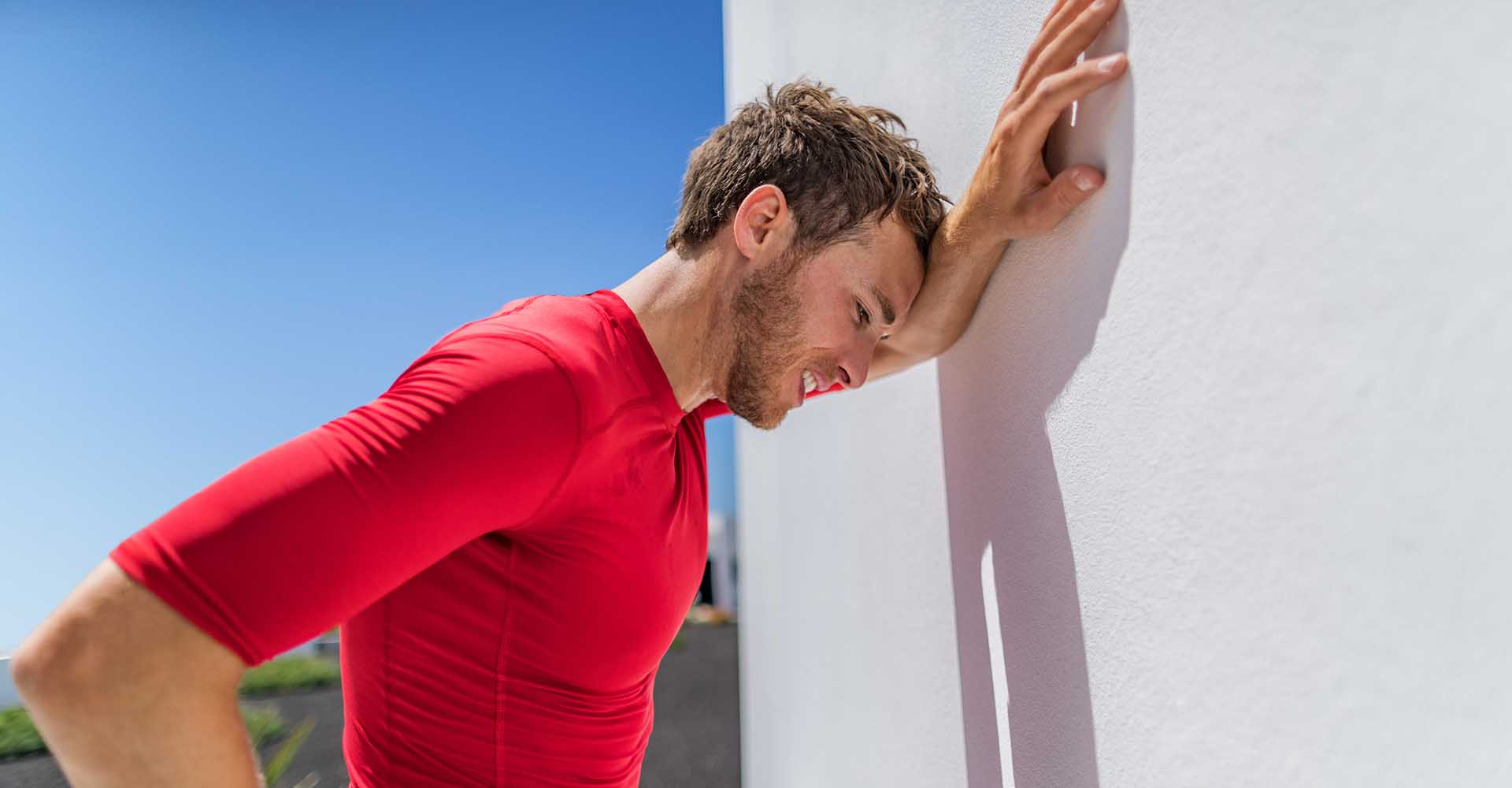 Exhausted man leaning on the wall due to fatigue breathing difficulty after doing physical exercises