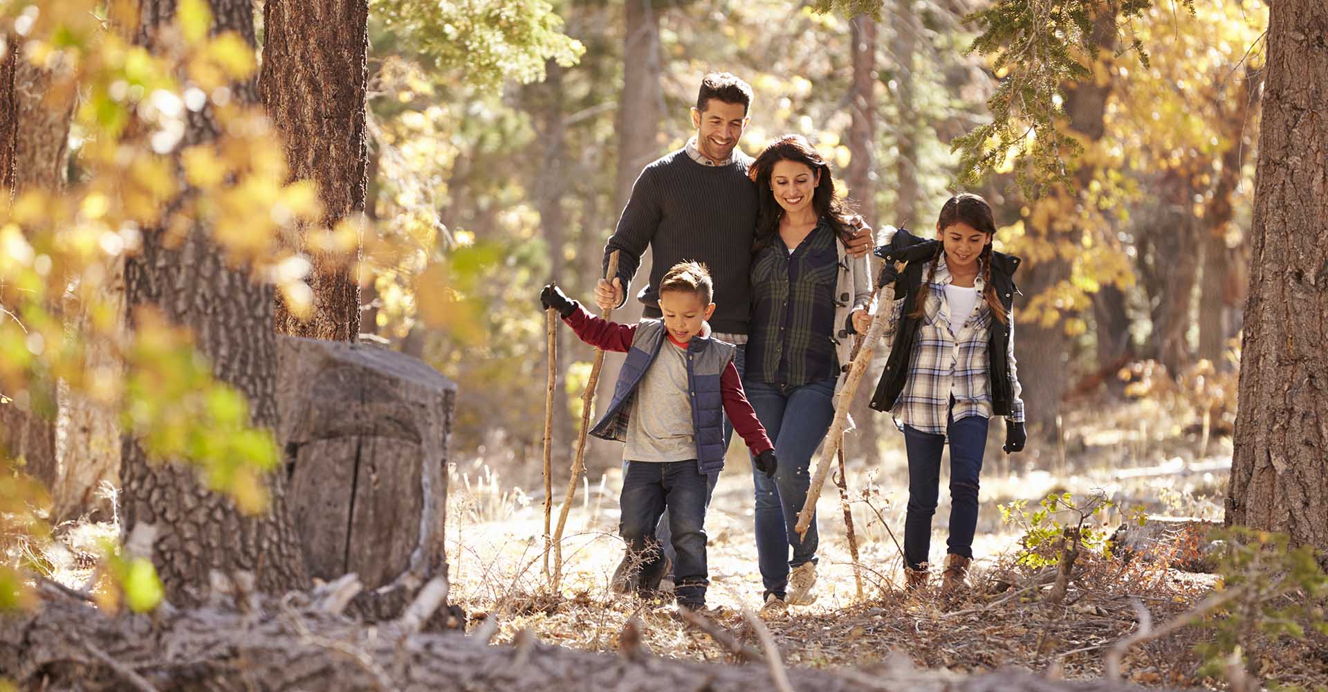 Happy Hispanic family with two children walking in a forest