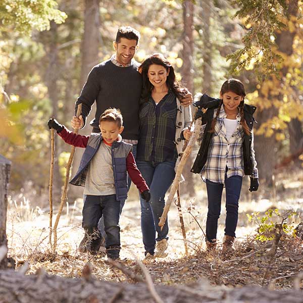 Happy Hispanic family with two children walking in a forest