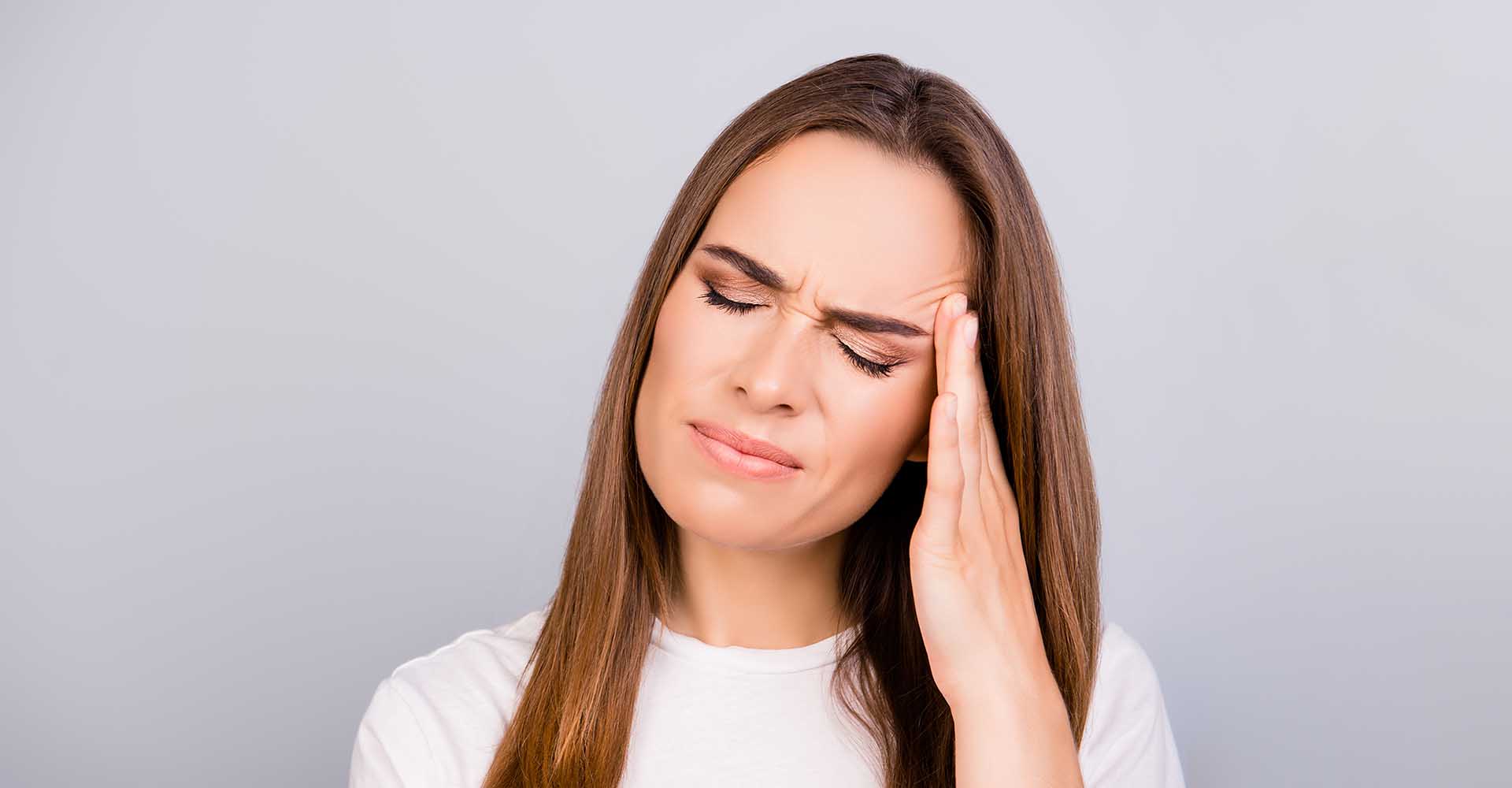 Beautiful woman suffering from strong migraine pressing her temple with her fingers